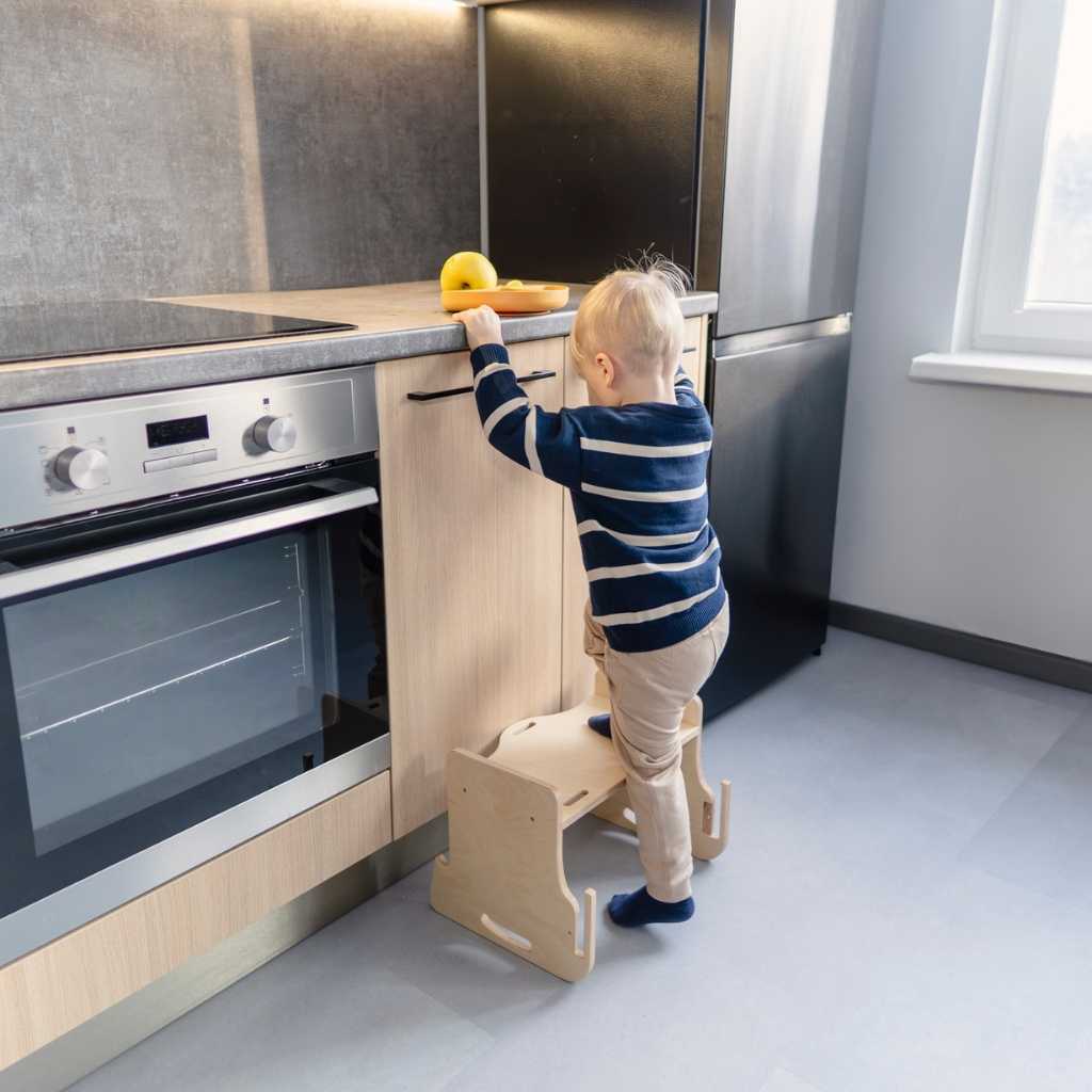 Toddler standing on a step stool converted from a transformable kitchen tower add-on