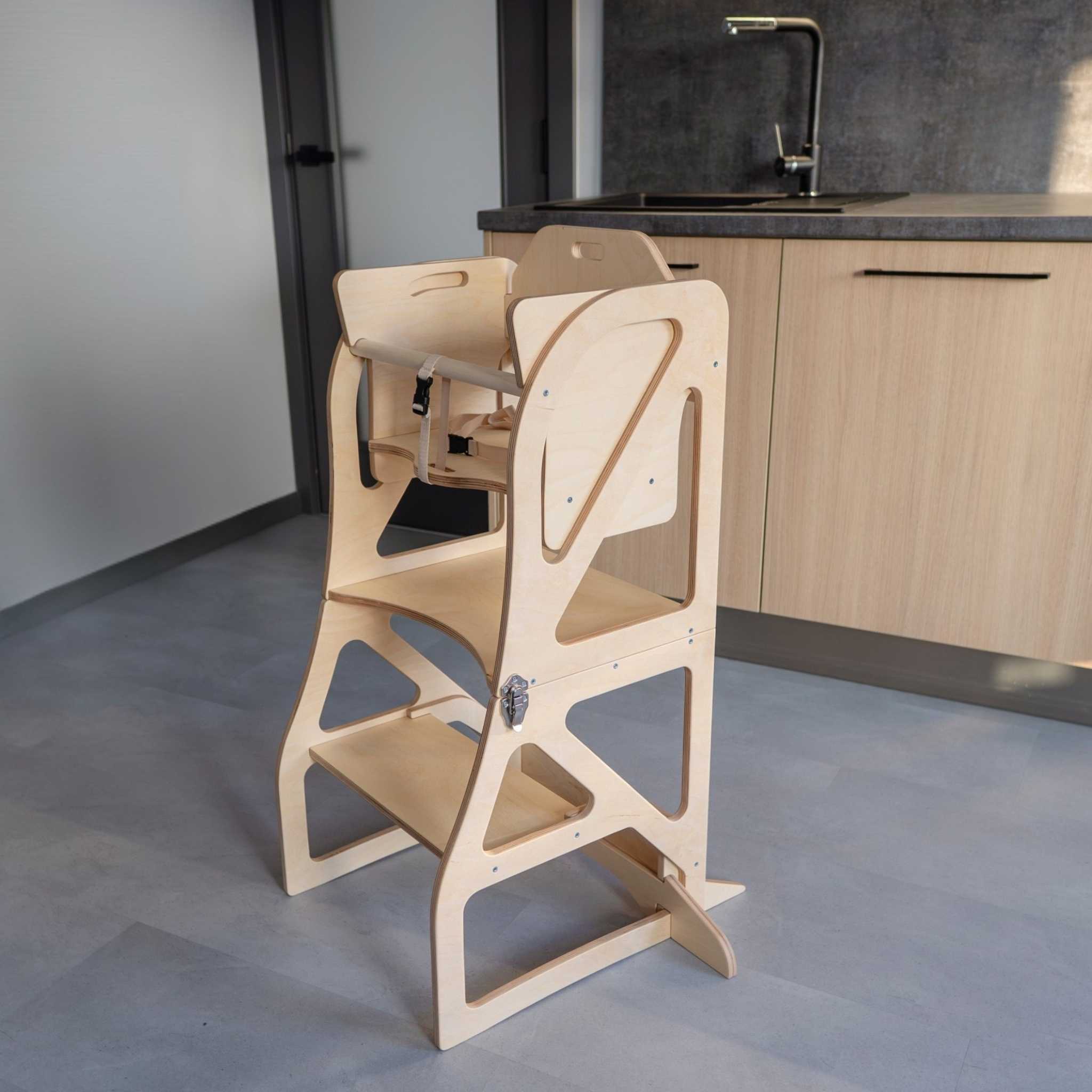 Transformable kitchen tower with high chair add-on used for safe toddler seating in the kitchen.