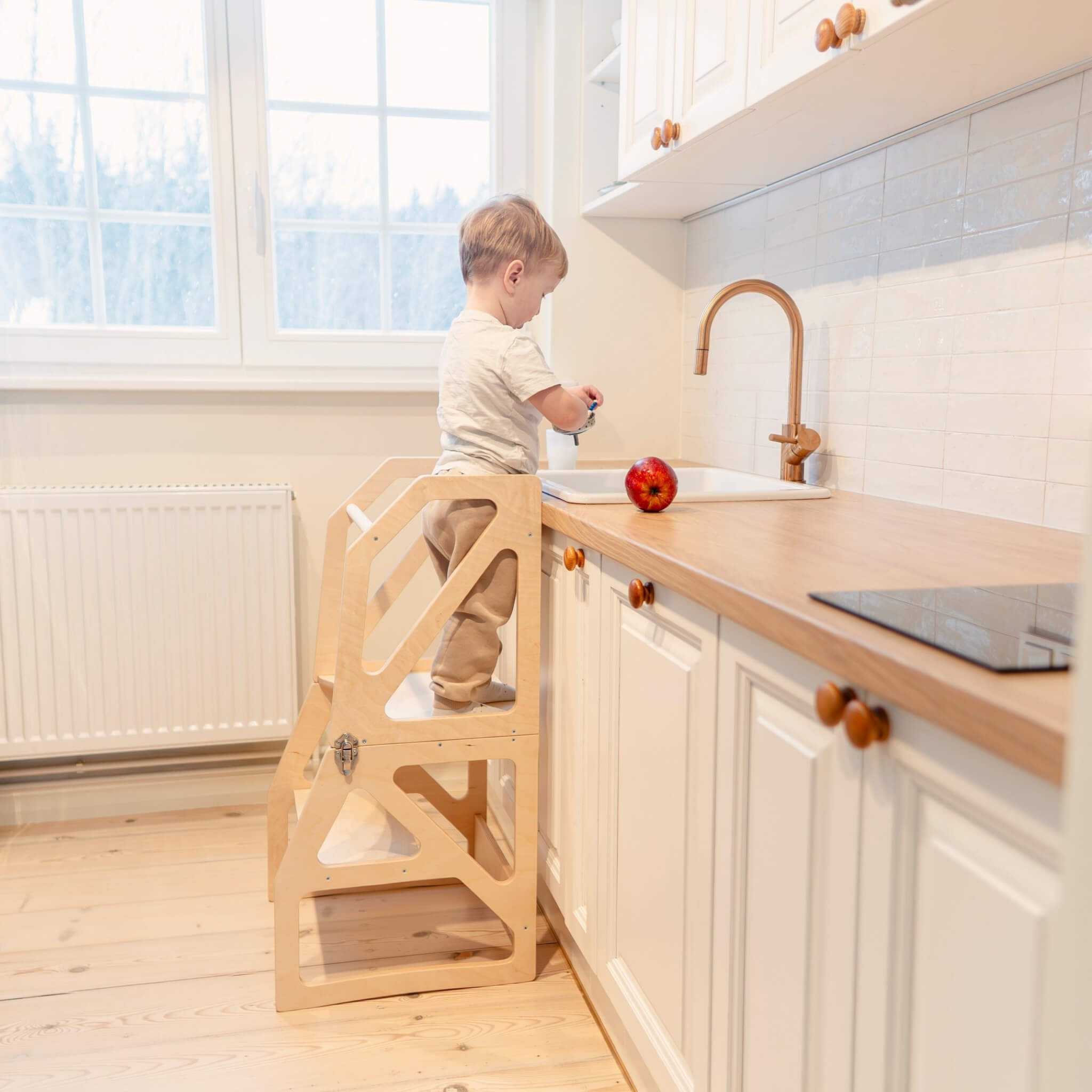Child washing hands using adjustable transformable kitchen tower at sink