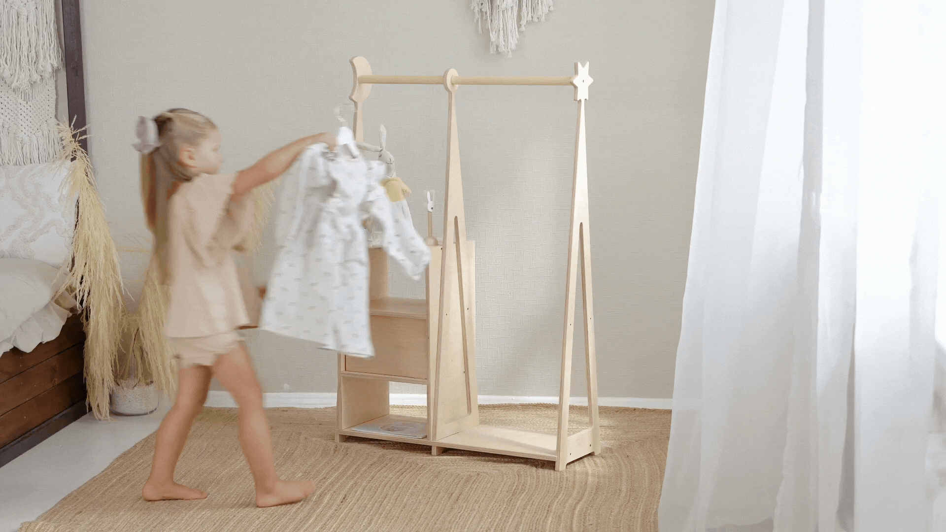Toddler hanging clothes on a Montessori clothing rack for independent dressing